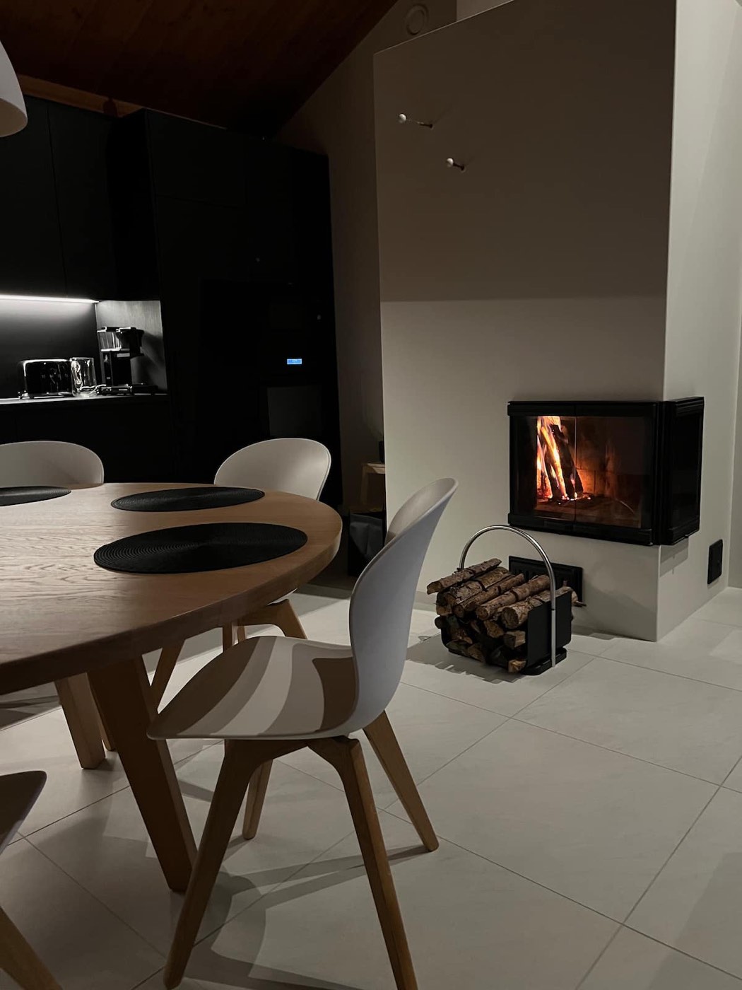 Wooden dining table set for dinner beside the fireplace