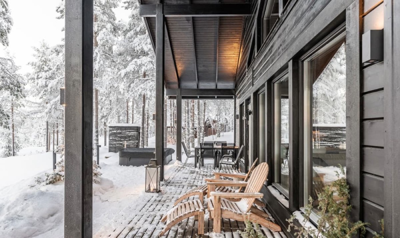 Covered terrace with sheepskin-lined chairs overlooking the snowy forest